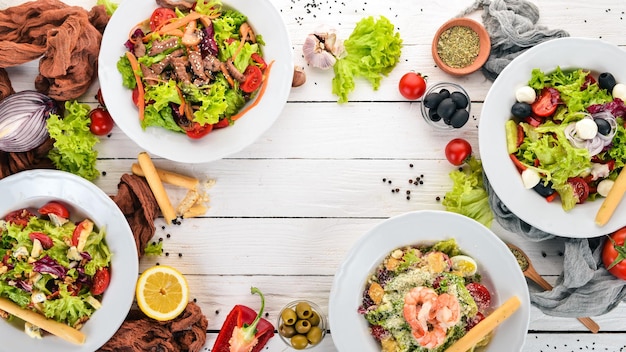 Assortment of fresh vegetables salads Healthy food On a white wooden background Top view Copy space for your text