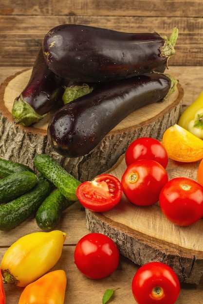 Assortment of fresh vegetables on a wooden background. Ripe tomatoes, eggplants, cucumbers and bell peppers, close up