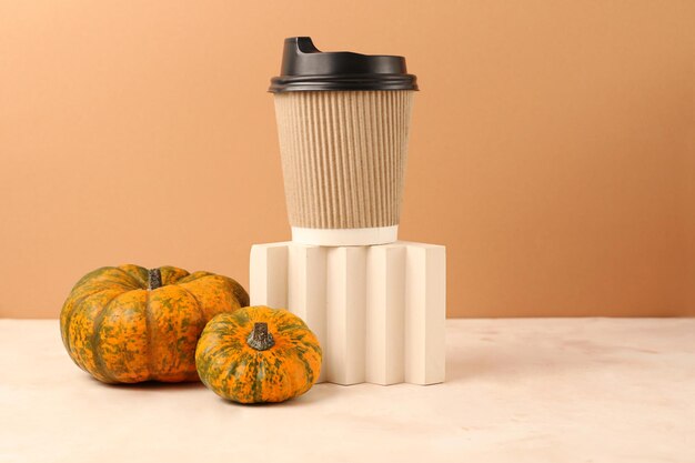 Assortment from pumpkins near geometrical podium with craft coffee cup