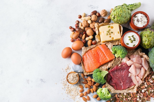 Assortment of healthy protein source and body building food Meat beef salmon chicken breast eggs dairy products cheese yogurt beans artichokes broccoli nuts oat meal Copy space background top view