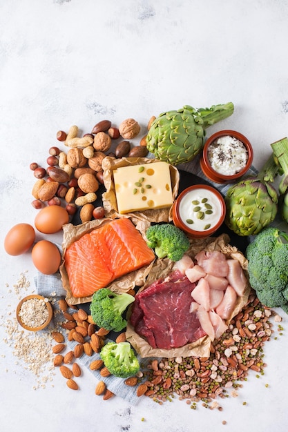 Assortment of healthy protein source and body building food Meat beef salmon chicken breast eggs dairy products cheese yogurt beans artichokes broccoli nuts oat meal Copy space background top view