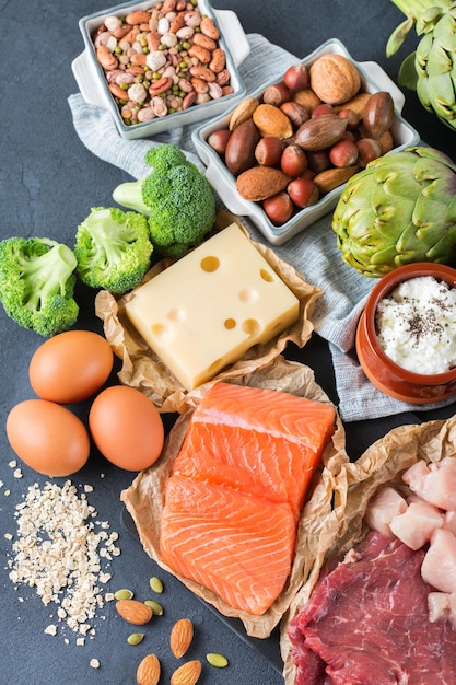 Assortment of healthy protein source and body building food Meat beef salmon chicken breast eggs dairy products cheese yogurt beans artichokes broccoli nuts oat meal Top view flat lay