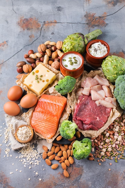 Assortment of healthy protein source and body building food Meat beef salmon chicken breast eggs dairy products cheese yogurt beans artichokes broccoli nuts oat meal Top view flat lay