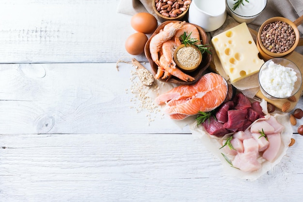 Assortment of healthy protein source and body building food Meat beef salmon chicken eggs dairy products milk cheese yogurt beans quinoa nuts oat meal Copy space background top view flat lay