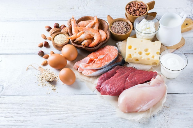 Assortment of healthy protein source and body building food Meat beef salmon chicken eggs dairy products milk cheese yogurt beans quinoa nuts oat meal Copy space background