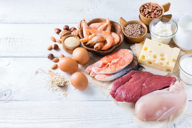 Assortment of healthy protein source and body building food Meat beef salmon chicken eggs dairy products milk cheese yogurt beans quinoa nuts oat meal Copy space background