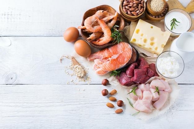 Assortment of healthy protein source and body building food Meat beef salmon shrimp chicken eggs dairy products milk cheese yogurt beans quinoa nuts oat meal Copy space background top view