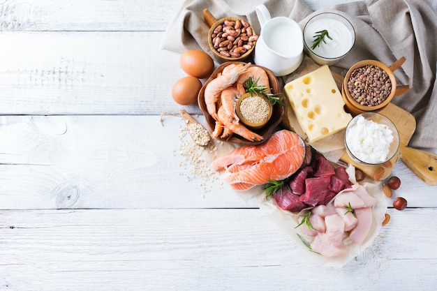 Assortment of healthy protein source and body building food Meat beef salmon shrimp chicken eggs dairy products milk cheese yogurt beans quinoa nuts oat meal Copy space background top view