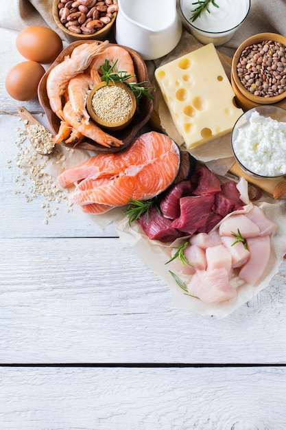 Assortment of healthy protein source and body building food Meat beef salmon shrimp chicken eggs dairy products milk cheese yogurt beans quinoa nuts oat meal Copy space background top view