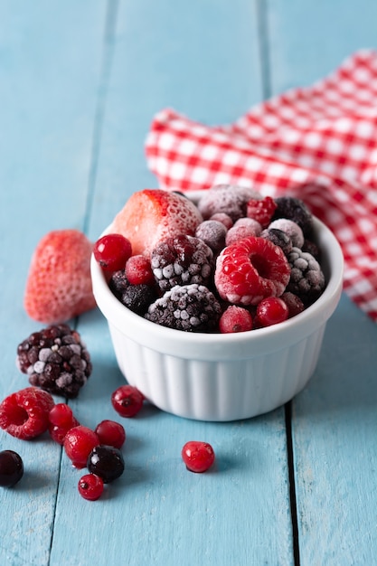 Assortment of iced berries in a bowl on blue wooden table