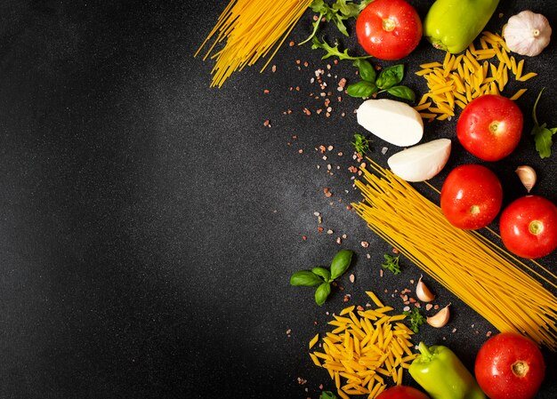 Ассортимент итальянских пищевых ингредиентов. Спагетти, пенне, моцарелла, базилик, помидоры, перец, руккола, чеснок. Концепция средиземноморской и итальянской кухни. Вид сверху.