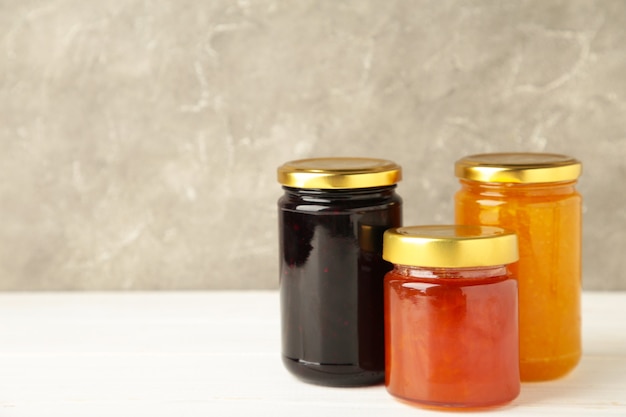 Assortment of jams, seasonal fresh berries and fruits on white background.