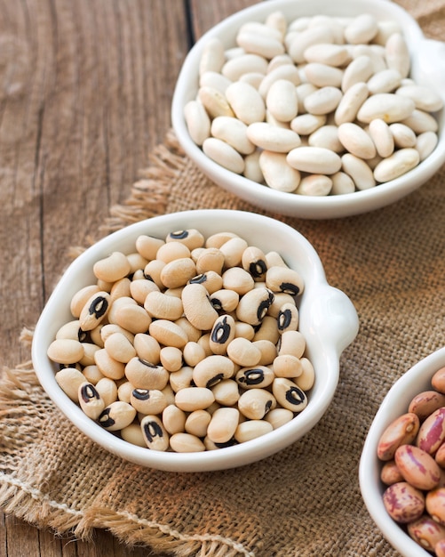 Assortment of legumes in bowls on wooden table close up