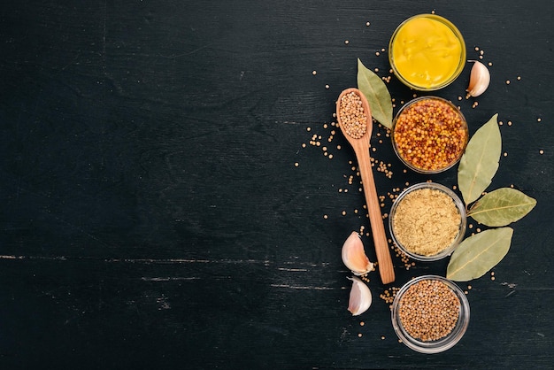 Assortment of mustard in sauces Spices On a black wooden background Top view Copy space for your text