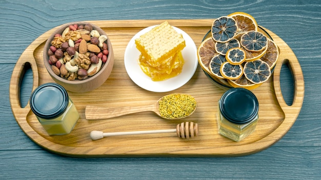 Assortment of nuts and assorted dried citrus fruits and fresh floral honeycomb honey on kitchen wooden board. useful vitamin food for the human body