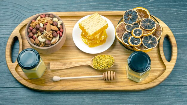 Assortment of nuts and assorted dried citrus fruits and fresh floral honeycomb honey on kitchen wooden board. useful vitamin food for the human body