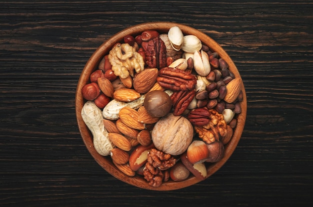 Assortment of nuts in bowls Cashews hazelnuts walnuts pistachios pecans pine nuts peanuts macadamia almonds brazil nuts Food mix on wooden background top view copy space