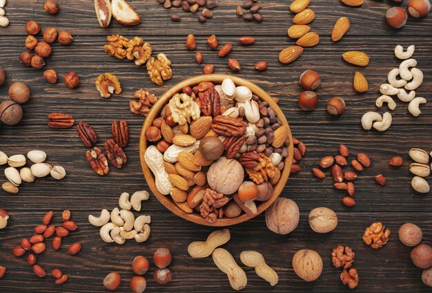 Assortment of nuts in bowls Cashews hazelnuts walnuts pistachios pecans pine nuts peanuts macadamia almonds brazil nuts Food mix on wooden background top view copy space