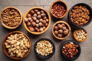 Assortment of nuts in bowls on stone background top view with copy space healthy snack food
