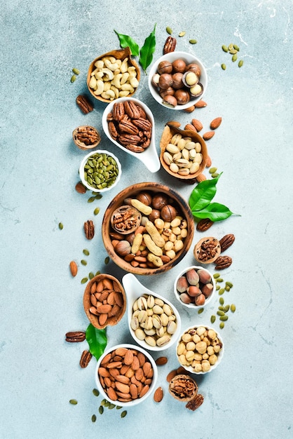 Photo assortment of nuts in bowls a variety of peeled nuts on a stone background top view