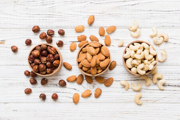 Photo assortment of nuts in wooden bowl on colored table cashew hazelnuts walnuts almonds mix of nuts top view with copy space