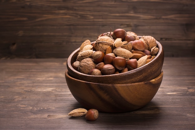 Assortment of nuts in wooden bowl ove rustic background