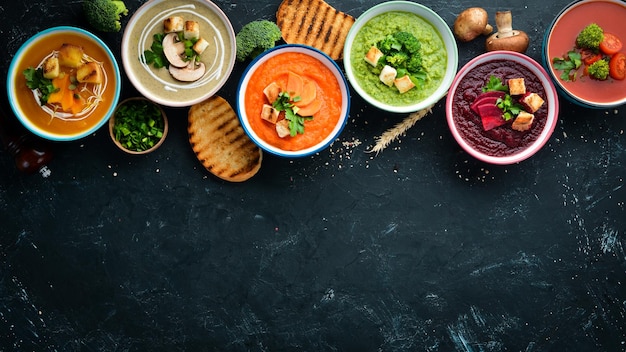 Фото Ассортимент цветных овощных крем-супов диетическое питание на фоне черного камня вид сверху бесплатное пространство для копирования