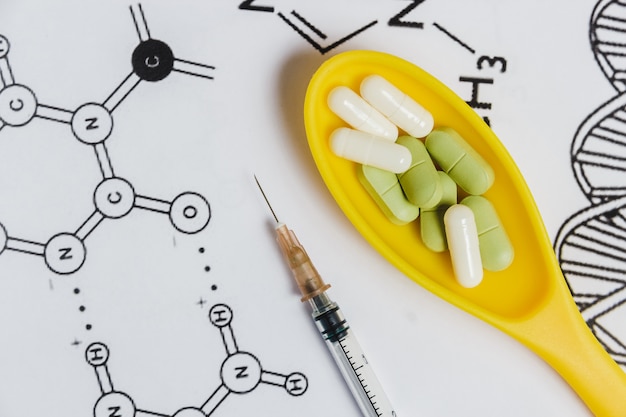 写真 薬、錠剤、カプセル、黄色のスプーン、化学式と白い背景の上の注射器の品揃え。