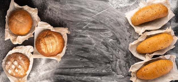 Фото Ассортимент различных вкусных свежевыпеченных хлебов на черном бетонном фоне с мукой верхнего обзора копировать пространство пекарни и здоровой пищи плоский плакат
