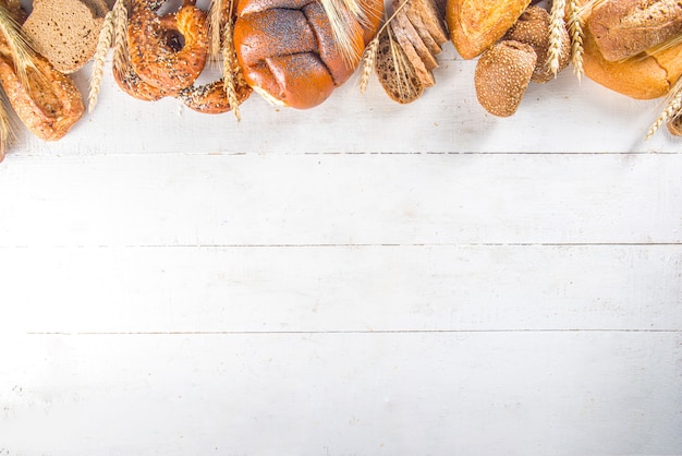 Фото Ассортимент различных вкусных свежеиспеченных хлеба, на белой поверхности с копией пространства