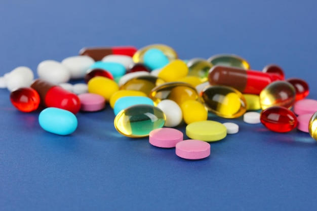 assortment of pills tablets and capsules on blue background
