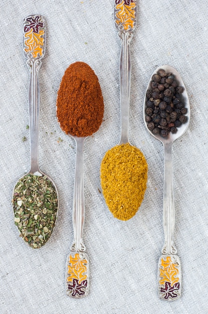 Assortment of powder spices on spoons on a light surface