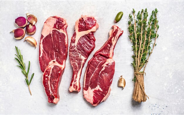 Assortment of raw cuts beef meat steaks on the bone Black background