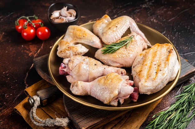 Assortment of Roast chicken meat parts on a plate Drumstick breast fillet wing thigh Dark background Top view