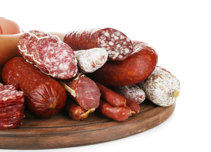 Photo assortment of sausages on wooden board isolated on white