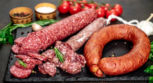 Assortment of smoked sausages and sausages with mold on a stone table