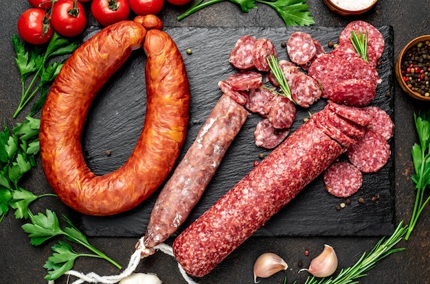 Assortment of smoked sausages and sausages with mold on a stone table