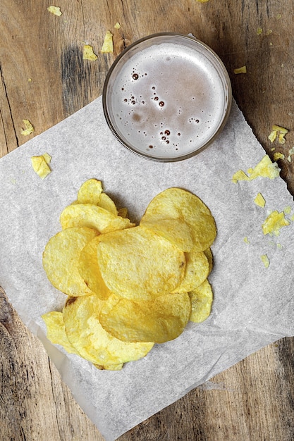 Assortment of Snacks at home with potato chips, beer, crackers, green and black olives on wood table