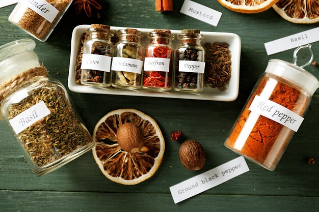 Photo assortment of spices in glass bottles on wooden background