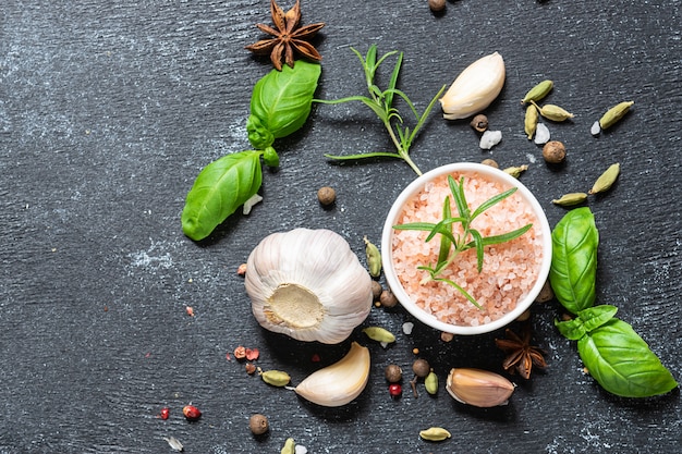 Assortment of spices, herbs and Himalaya salt on black stone background with copy space for your text.