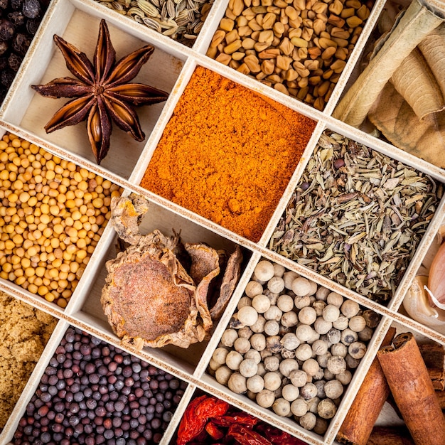 Assortimento di ingredienti di spezie in scatola di legno sul tavolo di legno.