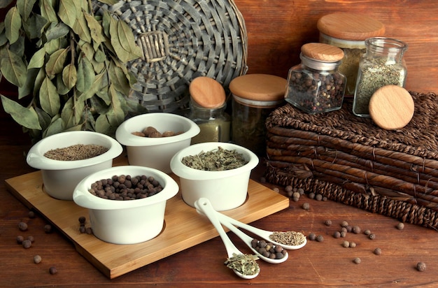 Assortment of spices in white spoons and bowls on wooden background