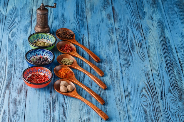 Assortment of spices in wooden spoons on wooden table