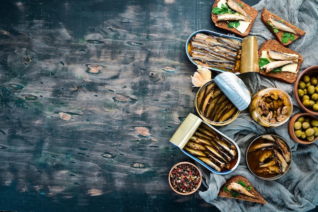 Assortment of sprats in oil. Smoked fish On a black background. top view. Free copy space.