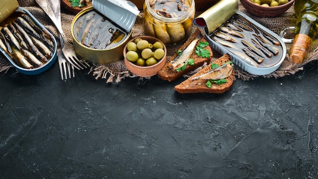 Assortment of sprats in oil Smoked fish On a black background top view Free copy space