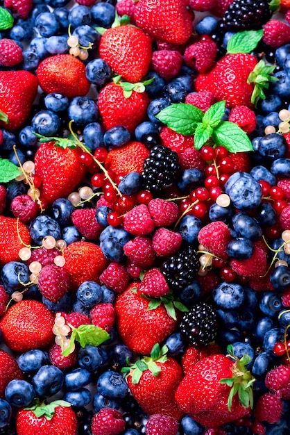 Assortment of strawberry blueberry raspberry blackberry currant mint Top view Summer food Macro of colorful berries background Vegan vegetarian and clean eating concept