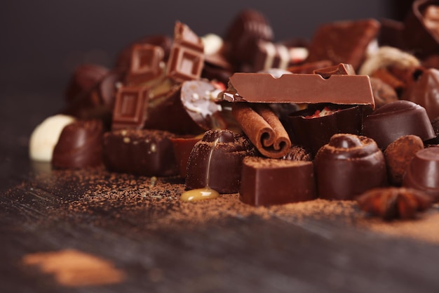 Assortment of tasty chocolate candies and cinnamon on wooden table background