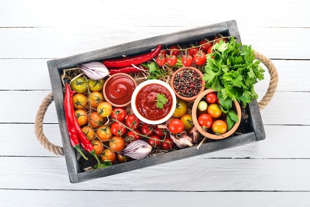 木製の箱に入ったトマトソースの品揃えケチャップチェリートマトスパイスチリペッパーオリーブオイルパセリ上面図