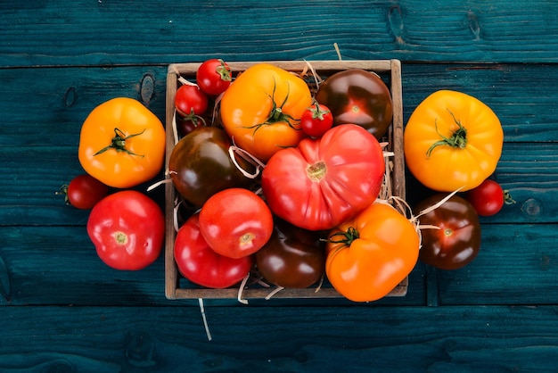 Assortment of tomatoes in a wooden box Fresh vegetables On a wooden background Top view Copy space