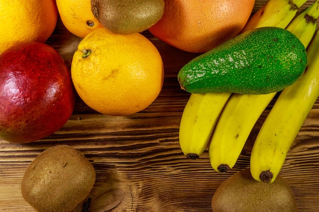 Ассортимент тропических фруктов на деревянном столе Натюрморт с бананами, манго, апельсинами, авокадо, грейпфрутом и киви Вид сверху